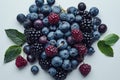 a pile of blueberries , raspberries , blackberries and cherries on a white surface Royalty Free Stock Photo