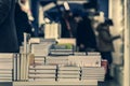 Pile of books, abstract blurred background in book store or in library. Unrecognizable people, bookshelves with books Royalty Free Stock Photo