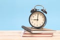 A pile of books and alarm clock on a wooden with blue background Royalty Free Stock Photo