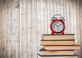 Pile of books and clock against blurry wood panel Royalty Free Stock Photo