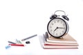 A pile of books and with coloured pen and alarm clock on white background Royalty Free Stock Photo