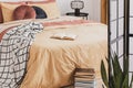 Pile of books in foot of king size bed with yellow duvet and ginger pillows