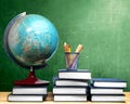 Pile of books and globe with pencils in basket container on wooden table Royalty Free Stock Photo