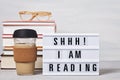 Pile of books, lightbox with the text, cup of coffee