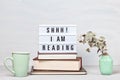 Pile of books, lightbox with the text, cup of coffee