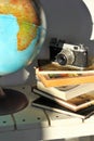 Pile of books, old film photo camera and a globe on white wooden table. Concept of travel, planning a dream trip Royalty Free Stock Photo