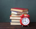 Pile of books and red alarm clock. Royalty Free Stock Photo