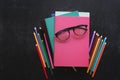 Pile of books, school stationery, glasses on slate black background. Back to school concept. Top view. Copy space. Free