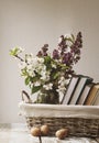 Pile of books and spring flowers of a lilac and apricot in a basket Royalty Free Stock Photo