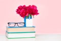A pile of books and a vase of flowers on a wooden table Royalty Free Stock Photo