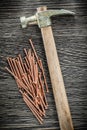 Pile of brass nails claw hammer on wooden board Royalty Free Stock Photo