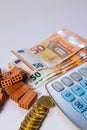 Pile of bricks, coins and euro notes next to a calculator on a white background. Home loan real estate for mortgage concept Royalty Free Stock Photo