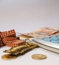 Pile of bricks, coins and euro notes next to a calculator on a white background. Home loan real estate for mortgage concept Royalty Free Stock Photo