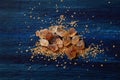 Pile of brown cane sugar, granulated sugar, large amber sugar crystals, blue wooden background