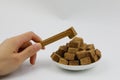 A pile of brown sugar cubes on a white plate woman hand hold wooden tweezers on white background Royalty Free Stock Photo