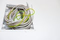 Pile of cables is hanging from a fuse box placed on the wall of unfinished building Royalty Free Stock Photo