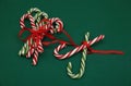 Pile Caramel sugar canes tied with a red ribbon on a green background. Christmas background. Concept of Christmas and New Year.