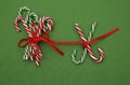 Pile Caramel sugar canes tied with a red ribbon on a green background. Christmas background. Concept of Christmas and New Year.