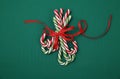 Pile Caramel sugar canes tied with a red ribbon on a green background. Christmas background. Concept of Christmas and New Year.