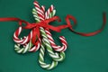 Pile Caramel sugar canes tied with a red ribbon on a green background. Christmas background. Concept of Christmas and New Year.