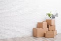 Pile of cardboard boxes and houseplant near white brick wall. Moving day Royalty Free Stock Photo