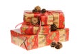 Pile of Christmas gifts wrapped with red and golden paper with ornaments and red glitter ribbon, decorated with pine cones. Royalty Free Stock Photo