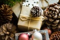 Pile of Christmas and New Year gift boxes wrapped in brown craft paper, pine cones, fir tree branches, baubles, wood ornaments Royalty Free Stock Photo