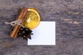 A pile of cinnamon sticks, dried orange, tree cone and white empy piece of paper with copy space. Idea for christmas card or