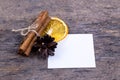 A pile of cinnamon sticks, dried orange, tree cone and white empy piece of paper with copy space. Idea for christmas card or