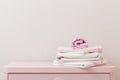 A pile of clean ironed bedding and a towel lies on the dresser