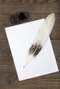 A pile of clean paper, a retro inkwell with black ink and a goose feather on a wooden table. Retro stylized photo. View from abov Royalty Free Stock Photo