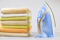 Pile of clothes and electric iron on the table on a light background. close-up of ironing tool and towels