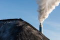 Pile of coal with the chimney of a coal power plant in the background. Royalty Free Stock Photo