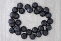 Pile of coal shaped candy in a round framed shape on a gray washed wood background