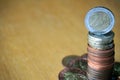 Pile of coins on the wooden table with a golden Euro coin on the top