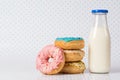 Pile of coloured donuts, pink donut and bottle of milk on polka dots background