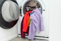 Pile of colorful clothes in a drum of a washing machine in laundry room