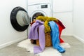 Pile of colorful clothes in laundry basket in front of a washing machine