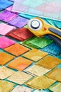 Pile of colorful fabric diamonds on cutter mat, quilting accessories