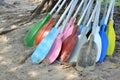 Pile of colorful kayak paddles on sand at the beach