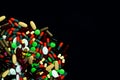 Pile of colorful tablets and capsules pills on black background. Global healthcare. Drug use in elderly people with chronic