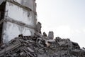 A pile of construction debris made of gray concrete fragments against the gray sky and the remains of a destroyed