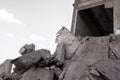 A pile of construction debris made of gray fragments of concrete slabs against the gray sky and the remains of a