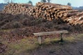 Pile of cut logs on heathland with bench in foreground