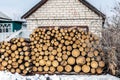 Pile of cutted wooden log stacked near house. Firewood timber material stack prepared for heating in winter at old rural building