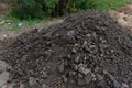 Pile of dark construction gardening soil mud land earth dirt heap pile mound, freshly dug, with some wet soil and leaves