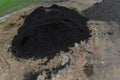 Pile of dark construction gardening soil mud land earth dirt heap pile mound, freshly dug, with some wet soil and leaves