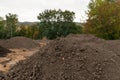 Pile of dark construction gardening soil mud land earth dirt heap pile mound, freshly dug, with some wet soil and leaves