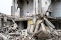 A pile of debris in the form of concrete slabs, piles, bricks on the background of the structure of the destroyed