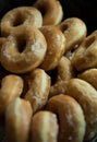 Pile of delicious sugar glazed donuts or doughnuts, with dark background and selective focus